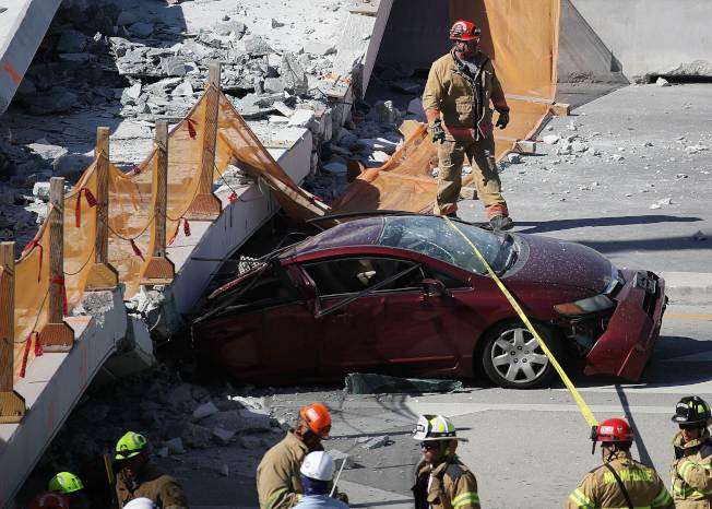 紧急救援人员试图从一辆被废墟压住的汽车里救人。（Getty Images）